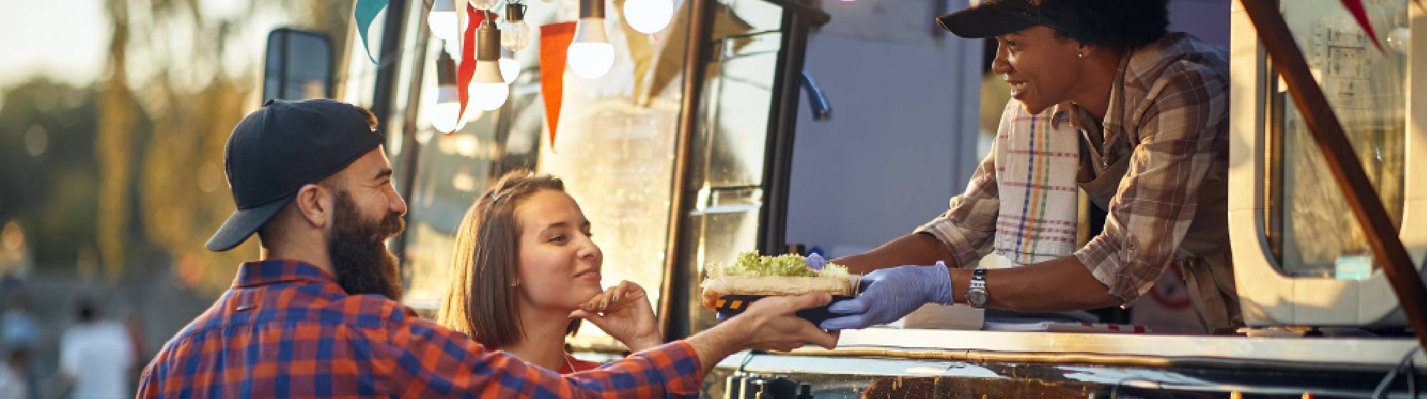 Des personnes en train d'acheter à manger à une dame dans son foodtruck. 